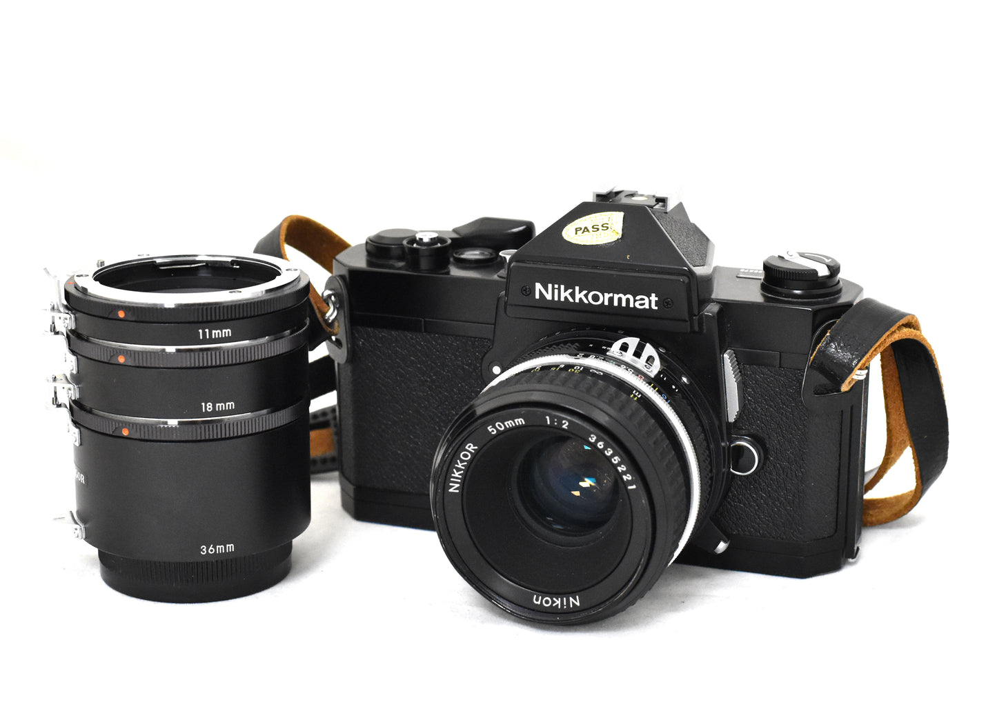 Nikkormat spegelreflexkamera med monterat Nikkor 50 mm f2 - objektiv, samt mellanringar på 11mm 18mm och 36mm kameran har rem